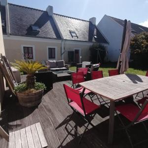 a patio with a wooden table and red chairs at Le Relais Côtier in Sauzon