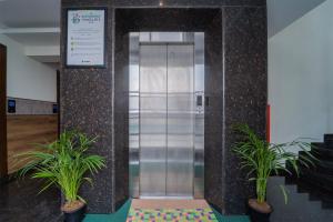 an elevator in a building with two potted plants at Treebo Viswa Vikas Residency in Coimbatore +27 photos