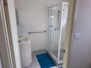 a bathroom with a shower and a blue rug at Toukley Lakeside Apartment in Toukley