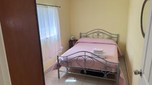 a bedroom with a bed with pink sheets and a window at Toukley Lakeside Apartment in Toukley