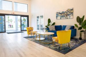 a living room with a blue couch and yellow chairs at Rodeway Inn Clearwater - Central in Clearwater