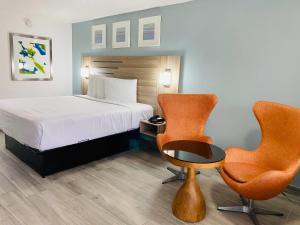 a hotel room with a bed and two chairs at Rodeway Inn Clearwater - Central in Clearwater