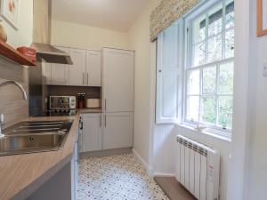 a kitchen with white cabinets and a sink and a window at South Segganwell - Culzean Castle in Maybole