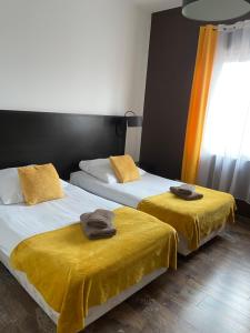 two beds in a room with yellow blankets on them at Hotel Altamira in Piotrków Trybunalski