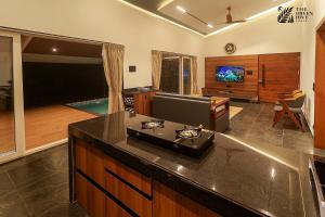 a living room with a kitchen with a couch and a tv at The Green Hive Villas in Belgaum