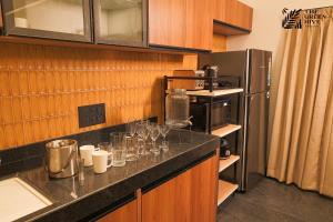 a kitchen with a counter with glasses and a refrigerator at The Green Hive Villas in Belgaum