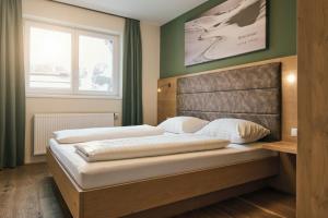 a bedroom with a bed with a headboard and a window at Almresort Gartnerkofel Nassfeld in Sonnenalpe Nassfeld