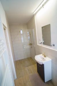 a white bathroom with a sink and a shower at Lumiere Studio 2 in Sfântu-Gheorghe +7 photos