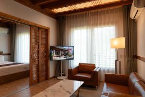 a hotel room with a bed and a couch and a television at Jeonju Wangyijimil Hanok Hotel in Jeonju