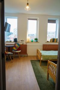a bedroom with a bed and a desk and two windows at Lumiere Studio 2 in Sfântu-Gheorghe