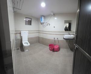 un bagno con un WC e un lavandino con due secchi rosa di Hotel New Rest Inn a Mahesāna