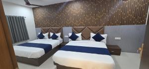 una camera da letto con due letti con cuscini blu e bianchi di Hotel New Rest Inn a Mahesāna Altre 25 foto