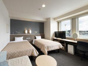 a hotel room with two beds and a desk at Onomichi Daiichi Hotel in Onomichi