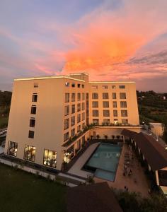a building with a swimming pool in front of a sunset at Aurum by R J Resorts in Siliguri +112 photos