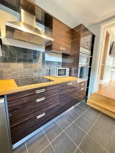 a kitchen with wooden cabinets and stainless steel appliances at Spacious 2 BR Flat in Gateshead - Free Parking in Gateshead