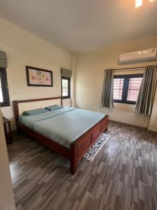 a bedroom with a large bed and wooden floors at พรพนาฮิล4 in Lamphun