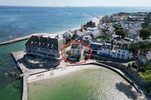 a building with a red circle on it next to the water at Villa authentique Vue mer 360 Les pieds dans l’eau in Larmor-Plage