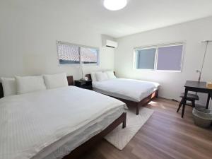 a white room with two beds and a desk at Black House in Yufu +6 photos