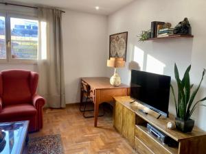 a living room with a television and a chair at Casco antiguo en Ribadesella in Ribadesella