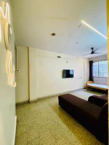 a room with a couch and a tv on the wall at Flora 2bhk Kothrud MIT WPU in Pune