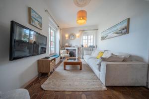 a living room with a couch and a flat screen tv at Villa authentique Vue mer 360 Les pieds dans l’eau in Larmor-Plage