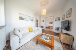 a living room with a white couch and a tv at Villa authentique Vue mer 360 Les pieds dans l’eau in Larmor-Plage