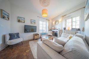a living room with a couch and a tv at Villa authentique Vue mer 360 Les pieds dans l’eau in Larmor-Plage