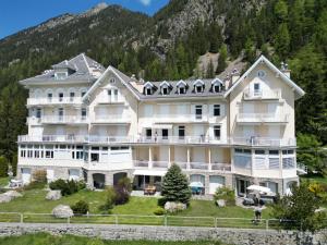 a large white building with a mountain in the background at Vache Mystique in Orsières