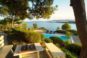 a bench next to a swimming pool with a view of the water at Villa Irini in Porto Heli