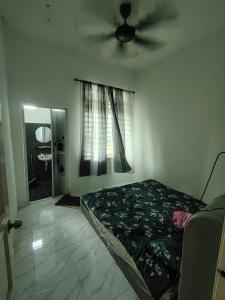 a bedroom with a bed and a ceiling fan at Miqayla Homestay in Wakaf Baharu