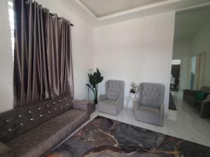 a living room with a couch and two chairs at Miqayla Homestay in Wakaf Baharu