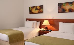 una habitación de hotel con 2 camas y una lámpara en Hotel Tativan, en Valledupar