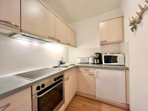 a kitchen with white cabinets and a sink and a microwave at Hirschzauber A9 Montana Haus in Oberstdorf