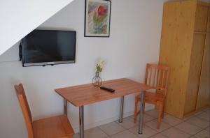a wooden table with a television and a table and chairs at Frühstückspension Stenbrock in Grevenbroich