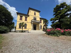 a yellow house with pink flowers on a gravel driveway at Villa Cervi in Ronco Todeschino