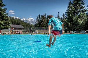 a man jumping into the water to catch a frisbee at Vache Mystique in Orsières