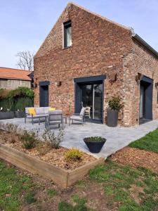 a brick building with a patio with couches and chairs at Gîte du Papillon CALUTRE Domaine du Papillon CALUTRE in Carvin