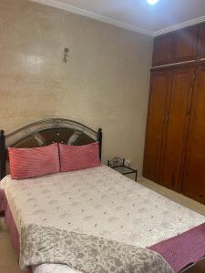 a bedroom with a bed with two pink pillows at Appartement Marrakech in Marrakesh