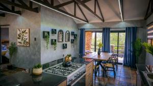 a kitchen with a stove and a dining room with a table at Idwala Le Ingwe Lodge in Hekpoort