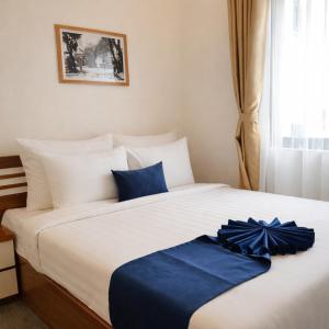 a bedroom with a large white bed with blue sheets at Sơn Lâm Hotel in Chợ Hiếu