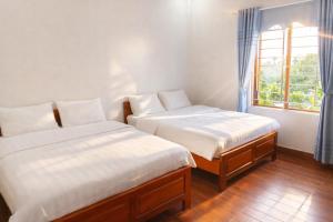two beds in a room with a window at Sơn Lâm Hotel in Chợ Hiếu