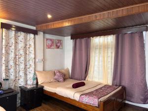 a bed in a bedroom with purple curtains at The Manzil Boho in Darjeeling