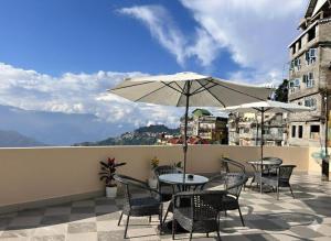 a patio with tables and chairs and an umbrella at The Manzil Boho in Darjeeling