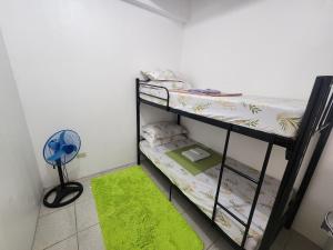a room with two bunk beds and a green rug at Caishen Apartelle 301 in Silang