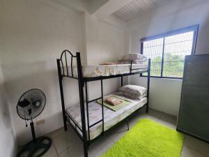 a room with two bunk beds and a fan at Caishen Apartelle 301 in Silang