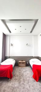 two beds in a room with red sheets at Noclegi Sezam in Łańcut +1 photo