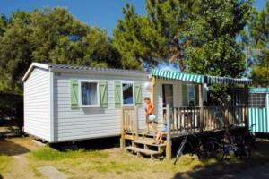a woman standing on the porch of a tiny house at ZEcamping animations espace aquatique piscine couverte et restaurant in Saint-Hilaire-de-Riez +27 photos
