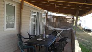 a patio with a table and chairs on a porch at ZEcamping 4 étoiles chiens acceptés piscine chauffée et toboggans in Portiragnes