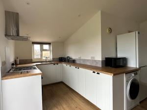 a kitchen with white cabinets and a washer and dryer at The Apple Press in Williton