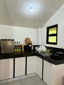 a kitchen with white cabinets and a black counter top at Namastay Siargao in General Luna